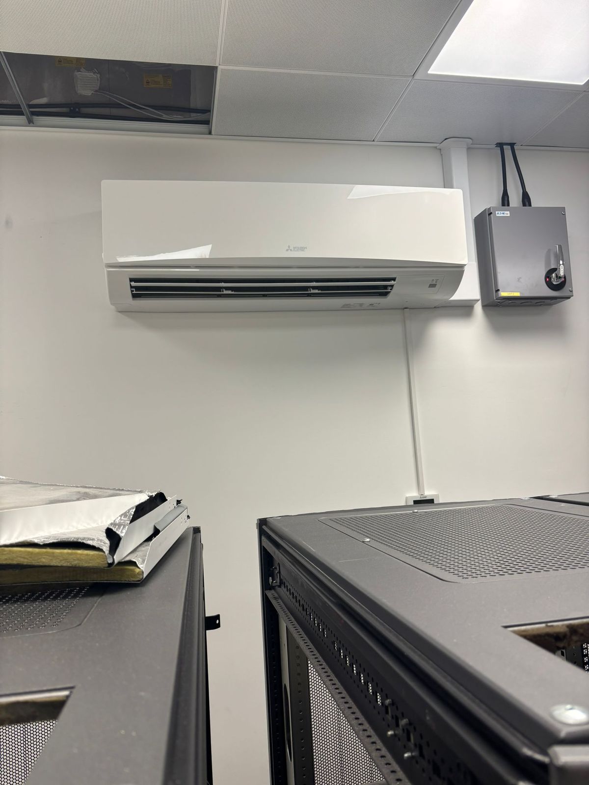 Wall-mounted air conditioning unit cooling a comms room with network cabinets