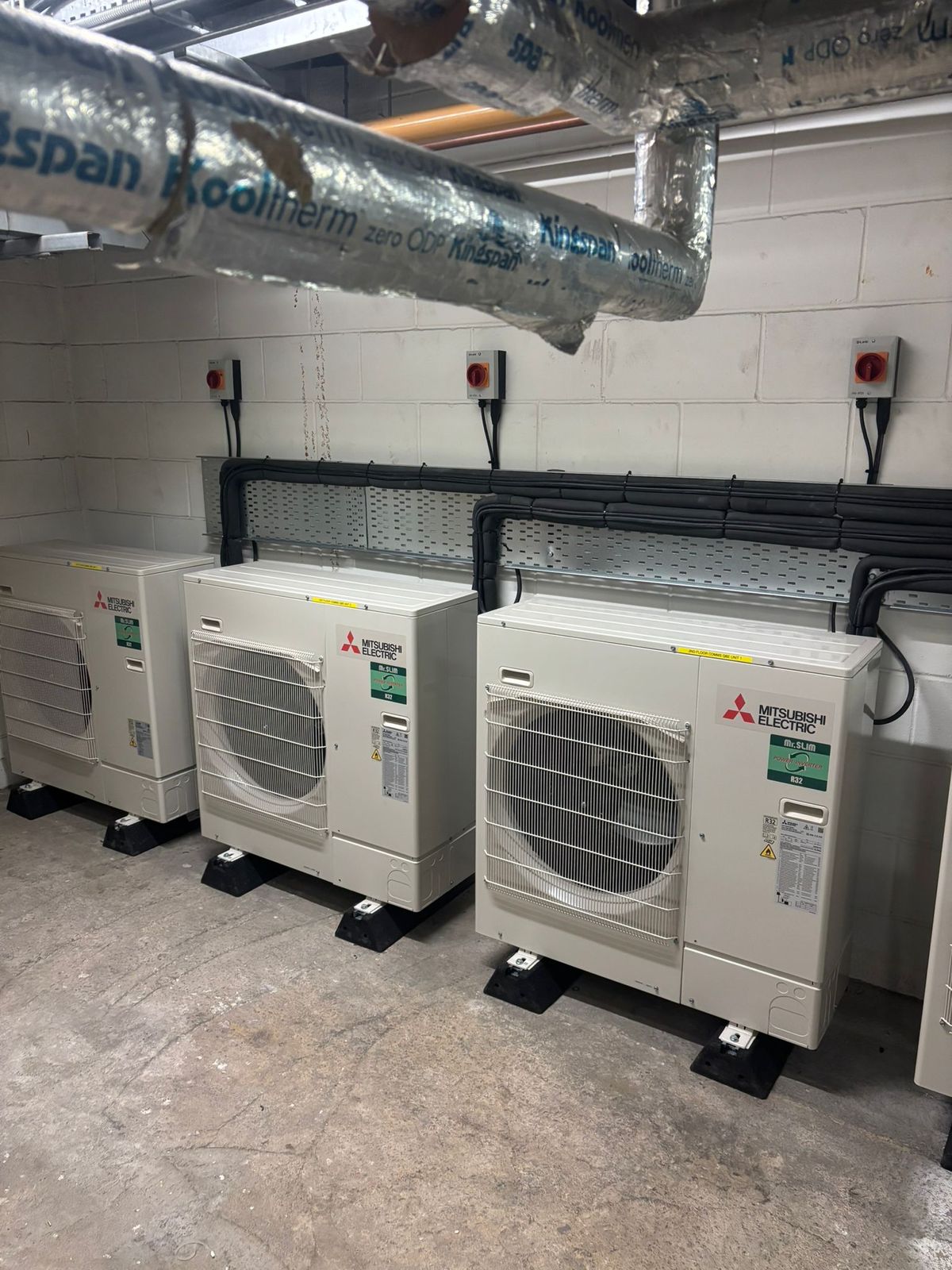 Three Mitsubishi Electric condensing units in a plant room below ductwork
