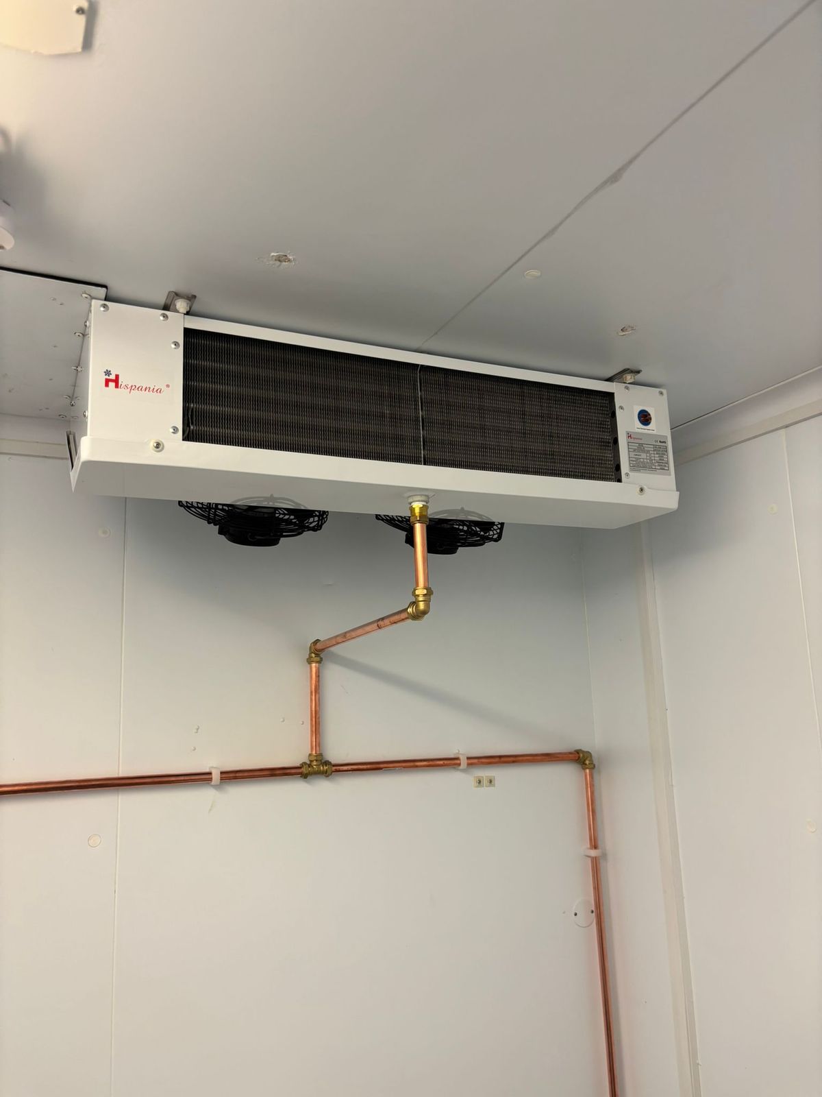 Cold room evaporator with copper pipework running down and along the wall