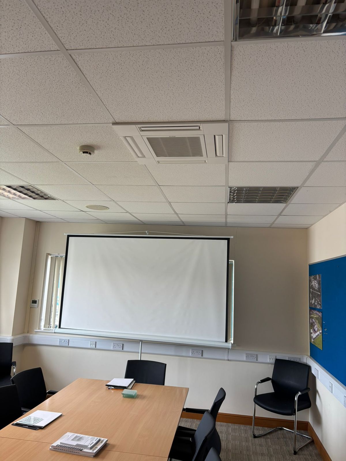 Ceiling cassette air conditioning unit in a meeting room with a projector screen